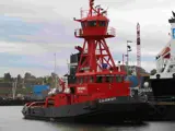 Red and black tugboat alongside