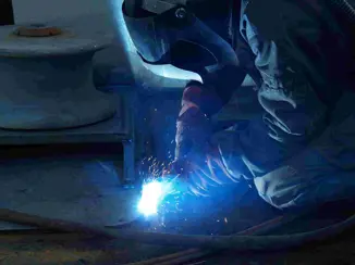 A person welding where the light from the welding is seen