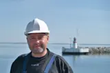 Man in black shirt and white helmet in front of lighthouse